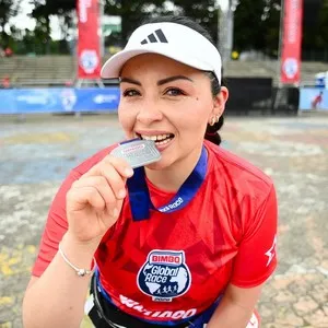 Participante celebrando con su medalla de la carrera